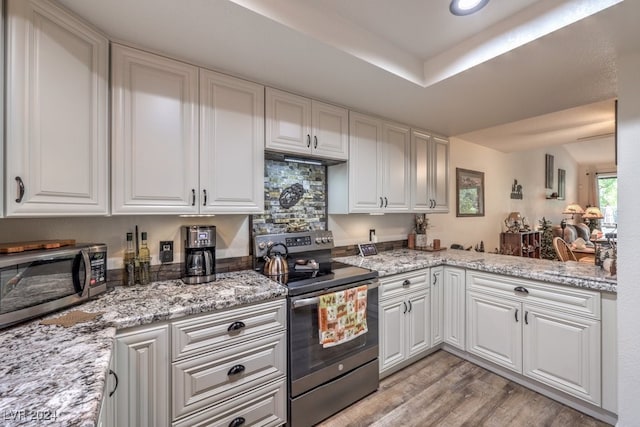 kitchen featuring white cabinets, light stone countertops, stainless steel appliances, and light hardwood / wood-style flooring