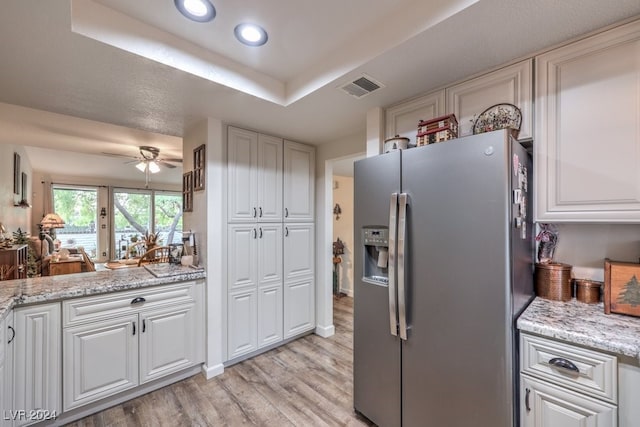 kitchen featuring white cabinets, ceiling fan, stainless steel fridge, light stone countertops, and light hardwood / wood-style floors