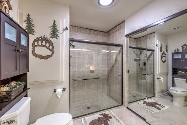 bathroom with tile patterned floors, toilet, and a shower with shower door