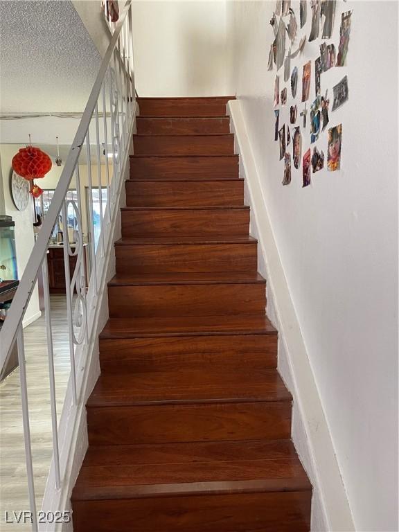 staircase featuring a textured ceiling and hardwood / wood-style flooring