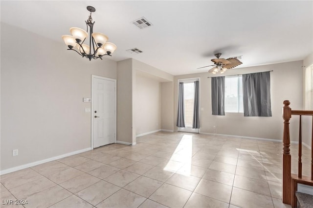 empty room with light tile patterned floors and ceiling fan with notable chandelier