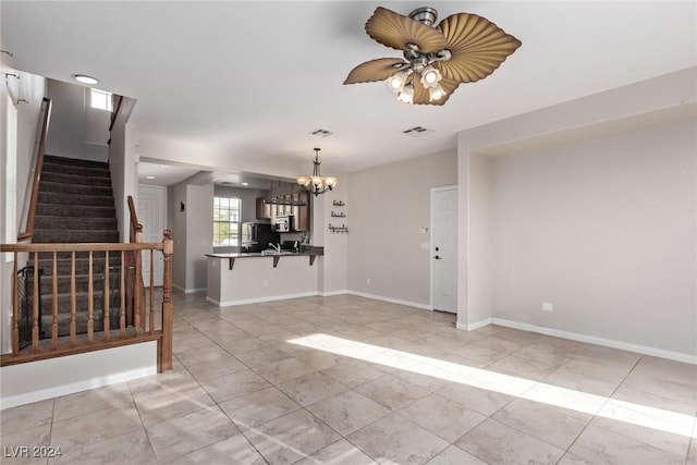 unfurnished living room featuring ceiling fan with notable chandelier