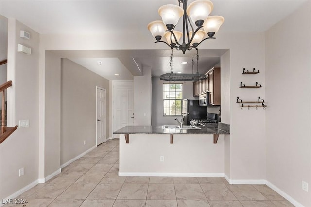 kitchen with kitchen peninsula, dark stone countertops, a chandelier, decorative light fixtures, and black appliances