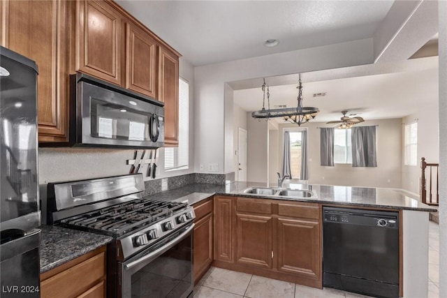 kitchen featuring ceiling fan, sink, kitchen peninsula, dark stone counters, and black appliances