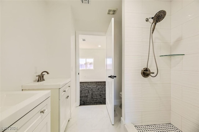 bathroom featuring vanity, toilet, and a tile shower