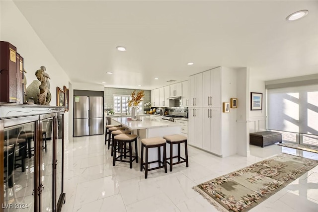 kitchen featuring range, a kitchen island, white cabinetry, a kitchen breakfast bar, and stainless steel fridge