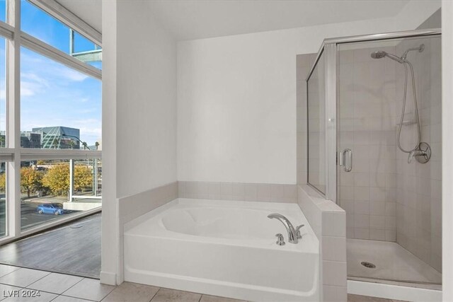 full bath with a bath, a shower stall, a city view, and tile patterned floors