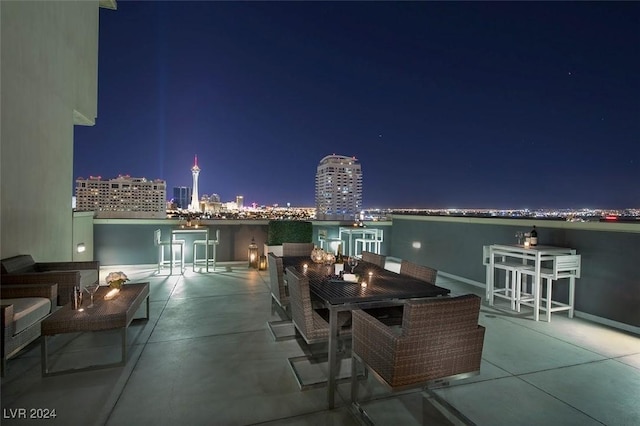 patio at twilight featuring a view of city lights and outdoor dining space