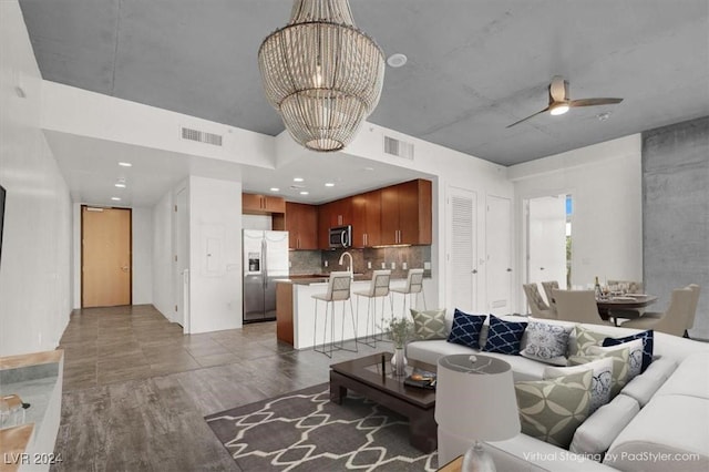 living room with wood finished floors, visible vents, and ceiling fan with notable chandelier