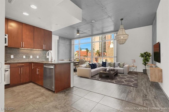 kitchen featuring tasteful backsplash, stainless steel dishwasher, open floor plan, a sink, and a peninsula