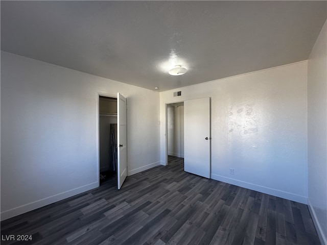 unfurnished bedroom featuring dark wood-type flooring and a closet