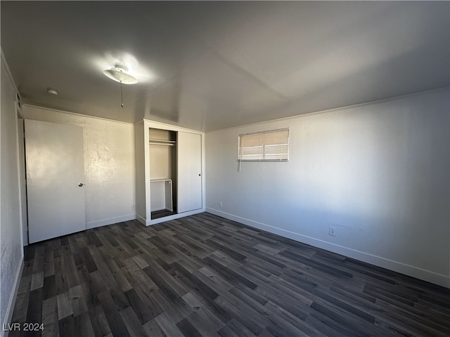 unfurnished bedroom with dark wood-type flooring and a closet