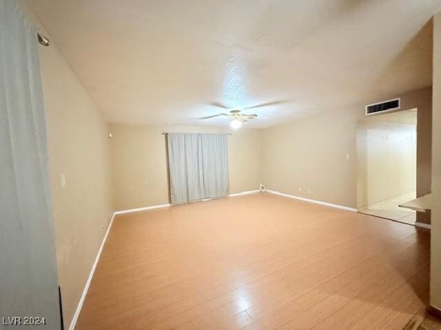 spare room with baseboards, visible vents, ceiling fan, and light wood finished floors