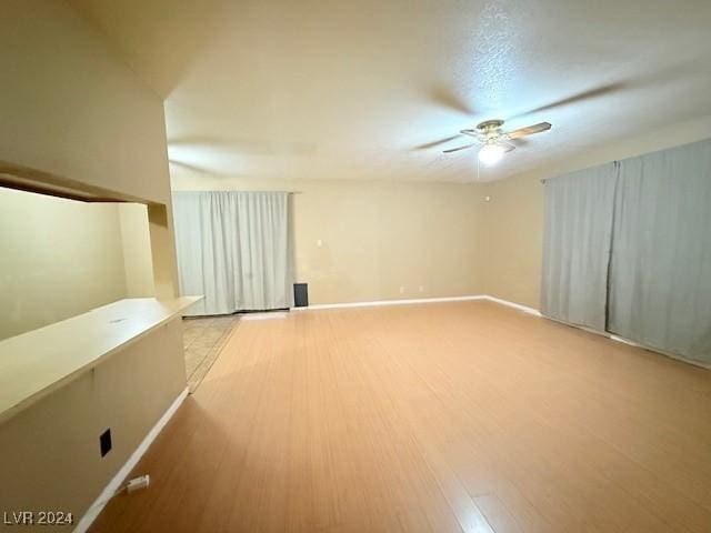 interior space with light wood-style flooring, baseboards, and a ceiling fan