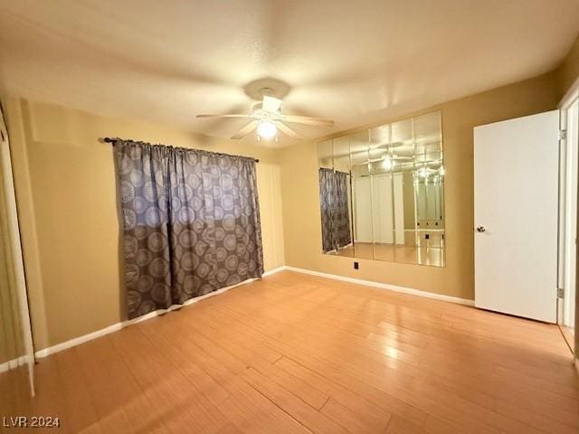 spare room featuring wood finished floors, a ceiling fan, and baseboards