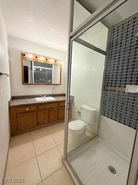 bathroom featuring vanity, a stall shower, tile patterned flooring, and toilet