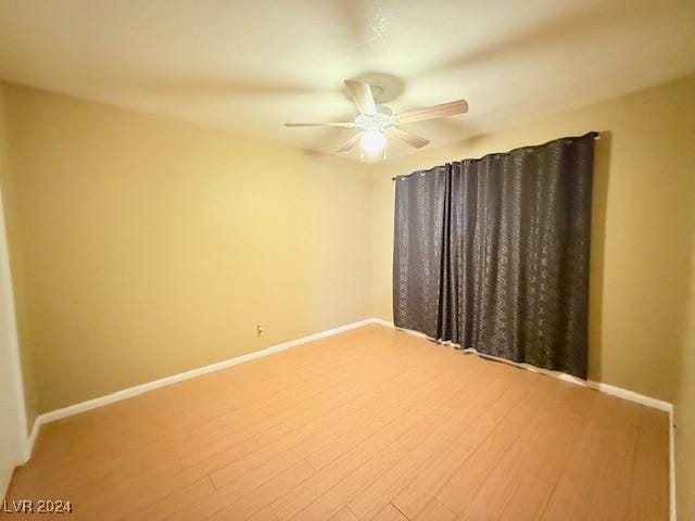 empty room featuring wood finished floors, a ceiling fan, and baseboards