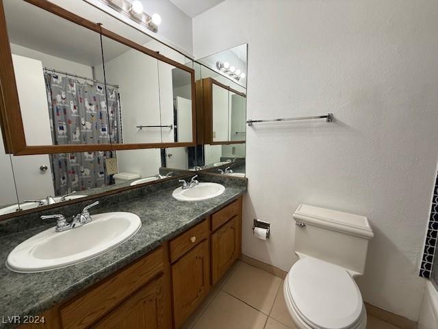 full bathroom with toilet, tile patterned flooring, double vanity, and a sink