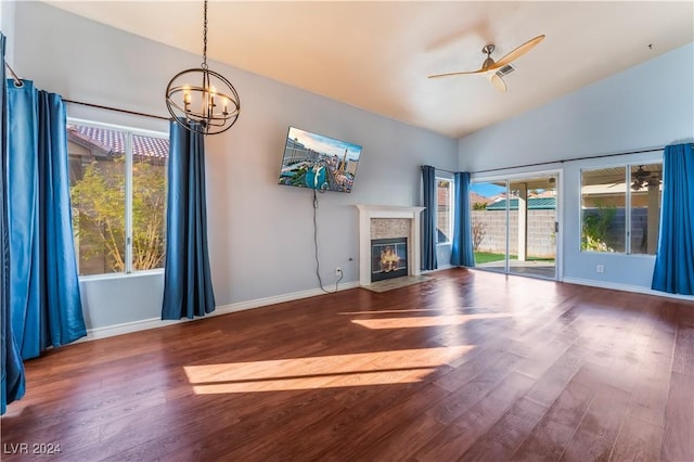 unfurnished living room featuring a healthy amount of sunlight, ceiling fan with notable chandelier, and wood-type flooring