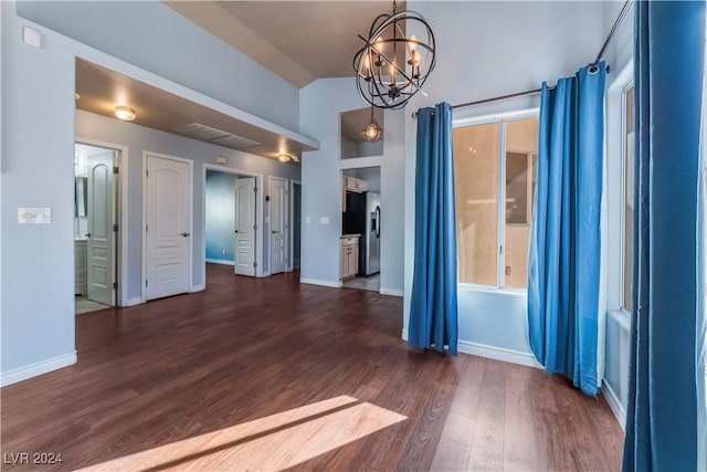 spare room featuring dark hardwood / wood-style floors, vaulted ceiling, and an inviting chandelier