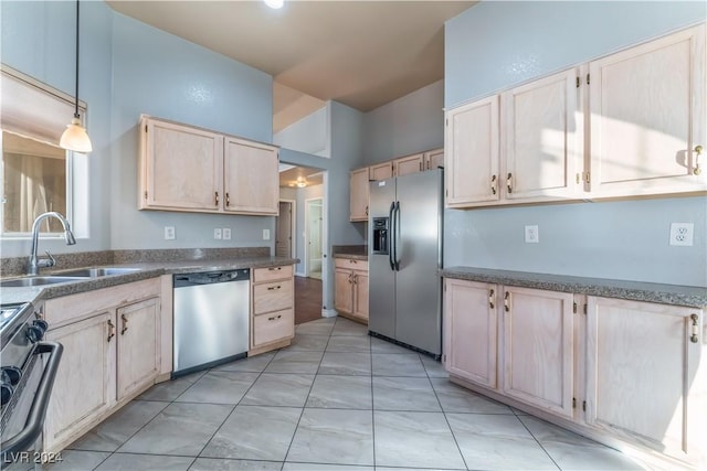 kitchen featuring appliances with stainless steel finishes, light brown cabinets, decorative light fixtures, and sink