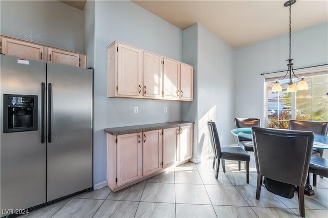 kitchen with stainless steel fridge, light brown cabinets, hanging light fixtures, and an inviting chandelier