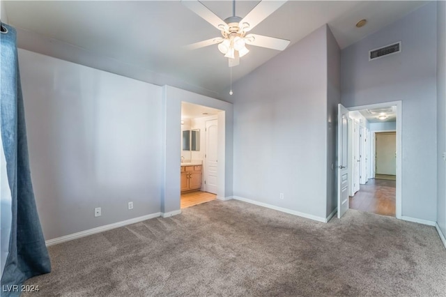 unfurnished bedroom with carpet flooring, connected bathroom, ceiling fan, and high vaulted ceiling