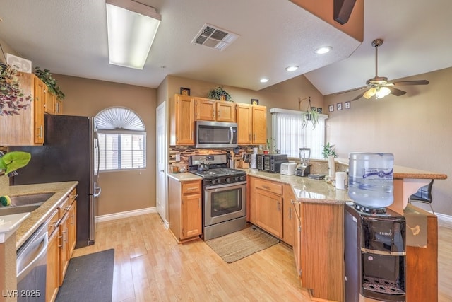 kitchen featuring stainless steel appliances, light wood-type flooring, ceiling fan, and a wealth of natural light