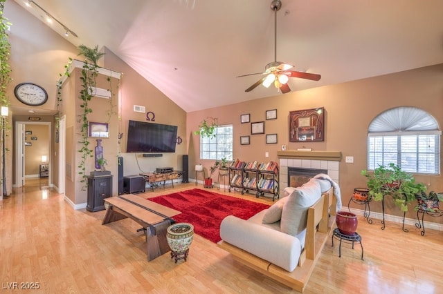 living room with ceiling fan, light hardwood / wood-style flooring, a tile fireplace, and plenty of natural light