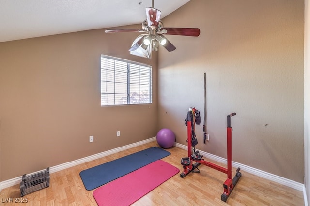 workout room with ceiling fan, vaulted ceiling, and hardwood / wood-style flooring