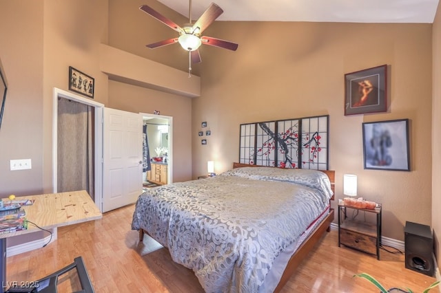 bedroom with ceiling fan, light hardwood / wood-style flooring, connected bathroom, and high vaulted ceiling