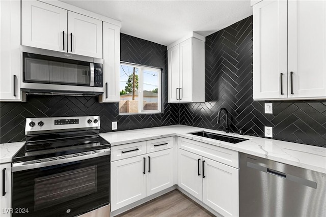 kitchen featuring light stone countertops, sink, stainless steel appliances, light hardwood / wood-style flooring, and white cabinets