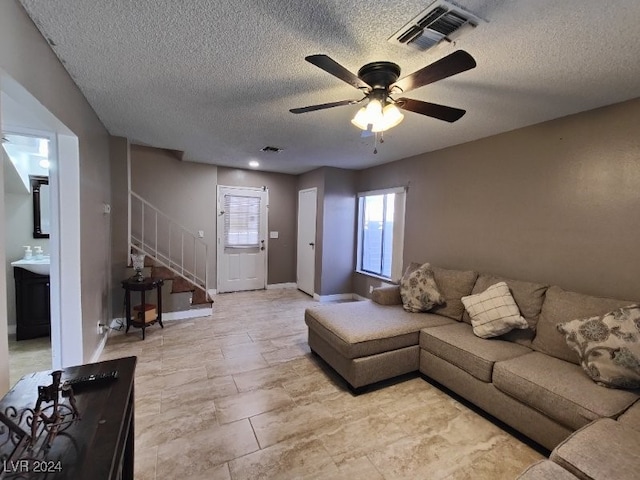 living room with a textured ceiling and ceiling fan