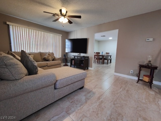 living room featuring ceiling fan and a textured ceiling