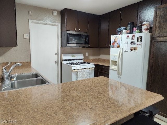 kitchen featuring a breakfast bar, white appliances, sink, dark brown cabinets, and kitchen peninsula