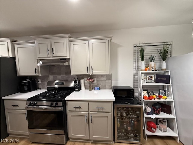 kitchen with gray cabinetry, stainless steel gas range, tasteful backsplash, wine cooler, and light hardwood / wood-style flooring