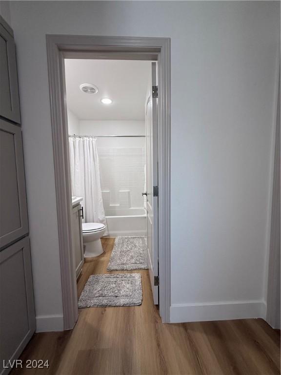 full bathroom featuring toilet, vanity, hardwood / wood-style flooring, and shower / tub combo with curtain