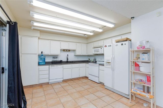 kitchen featuring white cabinetry, sink, light tile patterned floors, and white appliances