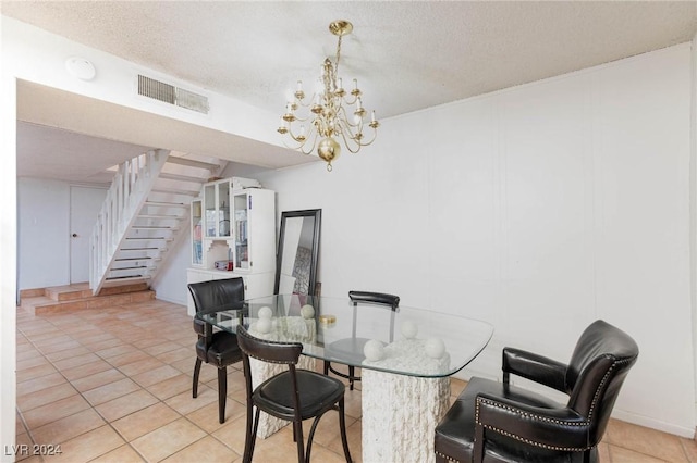 dining area featuring light tile patterned floors, a chandelier, and a textured ceiling