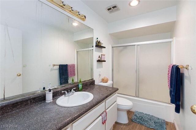 full bathroom featuring combined bath / shower with glass door, vanity, hardwood / wood-style flooring, and toilet