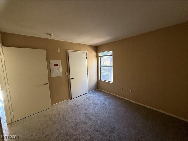 unfurnished bedroom featuring electric panel, a closet, and light colored carpet