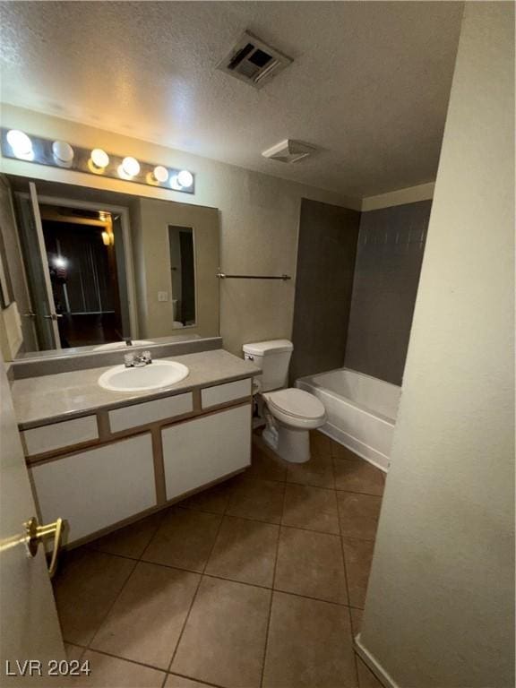 bathroom with tile patterned flooring, vanity, toilet, and a textured ceiling