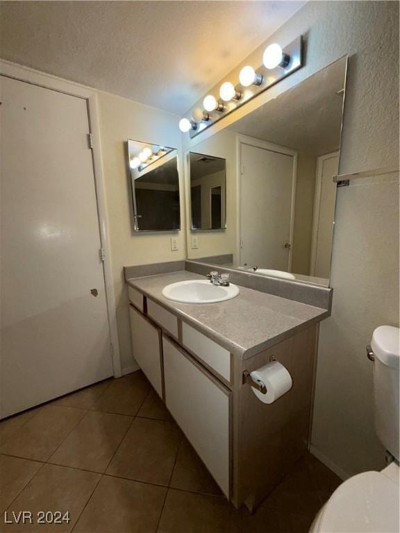 bathroom featuring tile patterned flooring, vanity, a textured ceiling, and toilet