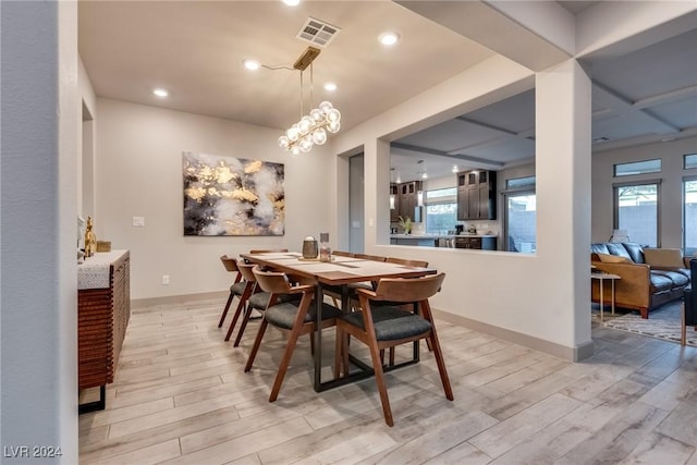 dining area with light hardwood / wood-style flooring and coffered ceiling