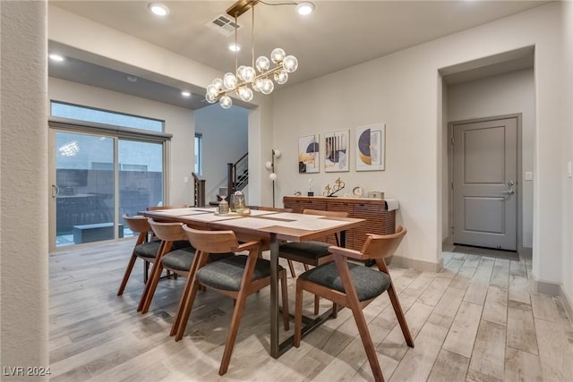 dining area with light hardwood / wood-style flooring and a notable chandelier