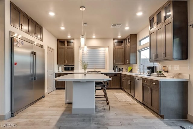 kitchen featuring a breakfast bar, sink, light hardwood / wood-style flooring, appliances with stainless steel finishes, and a kitchen island