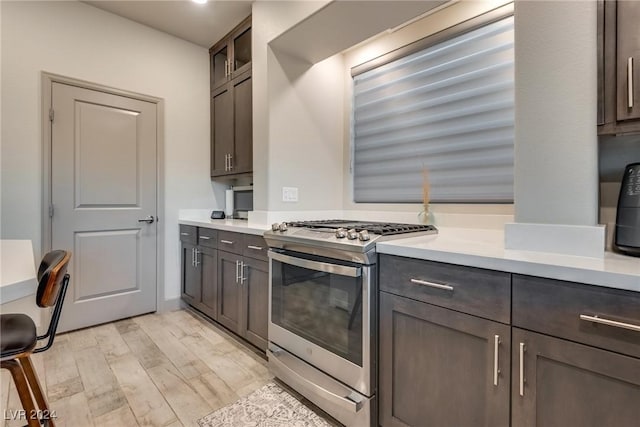 kitchen with dark brown cabinets, stainless steel gas stove, and light hardwood / wood-style floors