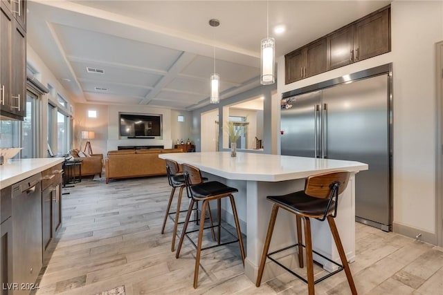 kitchen featuring a center island, stainless steel appliances, coffered ceiling, light hardwood / wood-style floors, and a kitchen bar