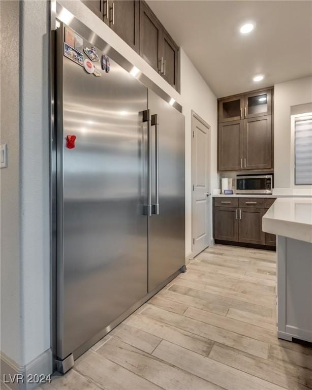 kitchen featuring dark brown cabinets, stainless steel appliances, and light wood-type flooring