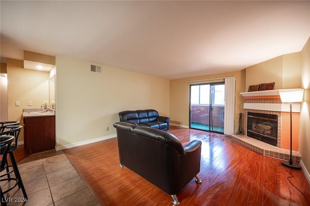 living room with sink, wood-type flooring, and a brick fireplace